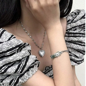 Détail du pendentif cœur argenté et bracelet boucle avec gravure vintage sur mannequin