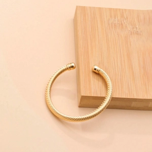 Minimalist golden twisted rope open bangle made of polished stainless steel for women