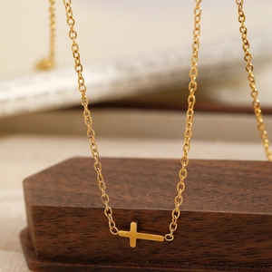 Close-up of minimalist gold cross pendant necklace on natural wooden background