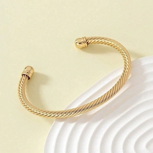 Detailed macro of gold twisted cable cuff bracelet with polished spherical end caps