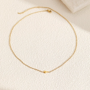 Close-up of minimalist gold stainless steel necklace with sideways cross pendant