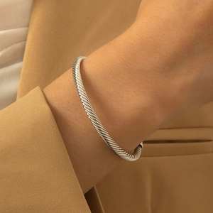 Silver twisted cable bangle bracelet featuring elegant metallic texture on model wrist