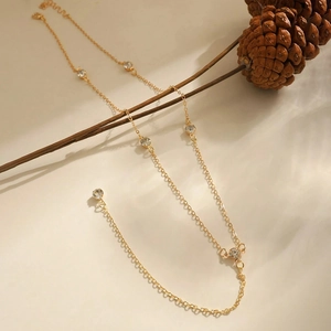 Close-up of a gold-plated Y-shaped necklace with round crystals on a warm natural background