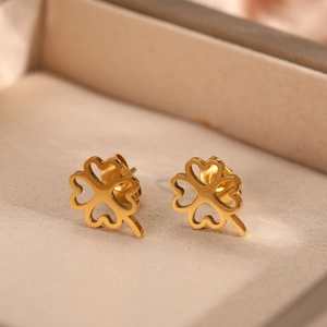 Vue macro de boucles d'oreilles trèfle en or avec détails de feuilles en forme de cœur