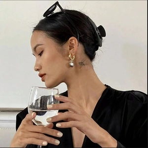 Two-tone heart drop earrings featuring gold hoops and silver pendants on a model