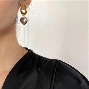 Minimalist heart pendant hoop earrings in mixed gold and silver tones on a female model