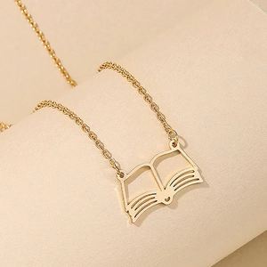 Macro view of a gold-toned open book pendant with a heart detail on a matching chain