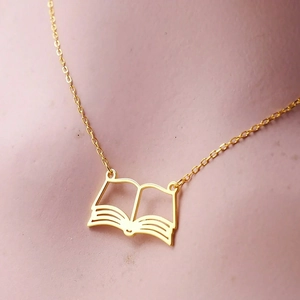 Macro shot of a golden hollow book pendant necklace with fine detailed link chain
