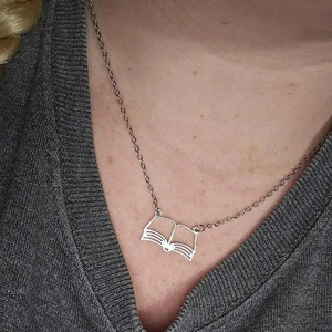 Detail of creative hollow book pendant necklace in silver stainless steel on collarbone