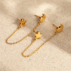 Bohemian gold crescent moon and star tassel earrings on beach sand background