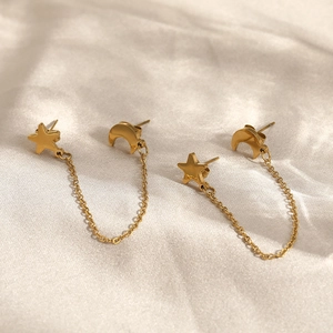 Golden stainless steel crescent moon and star tassel earrings on silk background