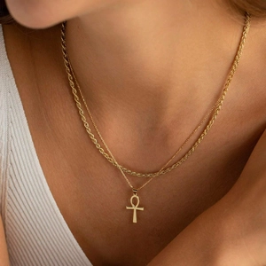 Detail of layered gold Ankh cross pendant and twisted rope chain necklace on model