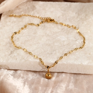 Detail of gold beaded anklet with lobster clasp and adjustable chain on stone texture