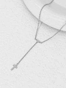 Detail of silver stainless steel necklace with heart link and cross pendant on stone