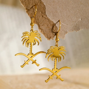 Détail macro de boucles d'oreilles emblème saoudien dorées avec palmier et sabres