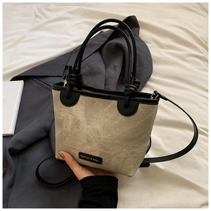 Close-up of stylish bucket bag featuring black leather trim and woven texture detail