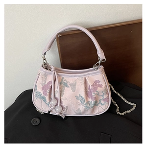 Detailed embroidery of purple flowers on a light pink brocade handbag with a gold chain