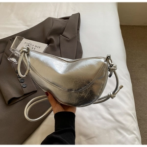 Detail of silver metallic dumpling bag with pleated texture and knotted shoulder strap