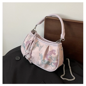 Close-up of floral embroidery on pink jacquard fabric with silver chain strap