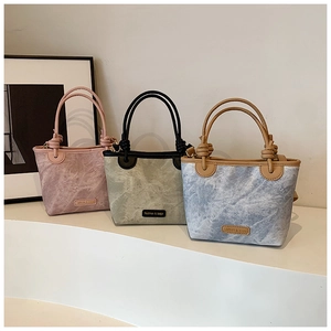 Detailed view of three minimalist bucket bags with marble texture and knotted rope handles