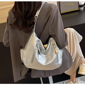 Close-up of the metallic silver tote bag texture with zipper details and side pocket