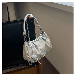 Detail of embroidered crane on beige fabric handbag with silver chain strap