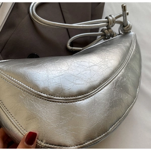 Detailed view of silver crescent bag featuring metallic crackle texture and knotted strap