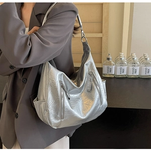Detail of silver metallic hobo bag featuring zip pockets and glossy crinkled texture