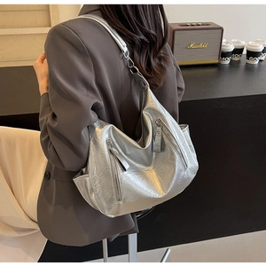 Detail of silver metallic tote bag with crinkled texture and front zipper pockets
