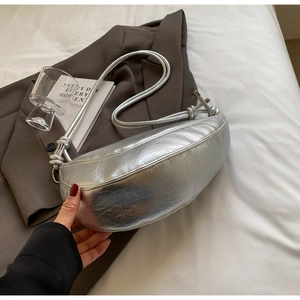 Close-up of metallic silver crescent bag with ruched texture on grey blazer