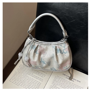 Detail of floral embroidery on a beige fabric handbag with silver metal handle and chain