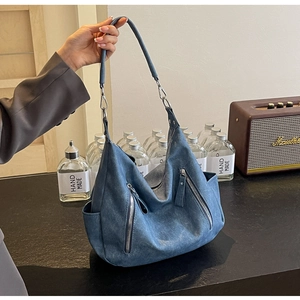 Detail of a large vintage denim blue tote bag with silver zippers and soft texture