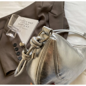 Close-up of metallic silver bag texture with vintage crackle effect and knotted handle
