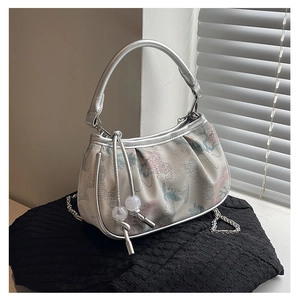 Detail of floral crane embroidery on silver jacquard bag with metallic handle and bead charm