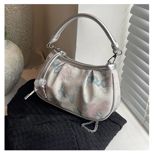 Detail of embroidered floral jacquard handbag with silver handle and beaded tassel