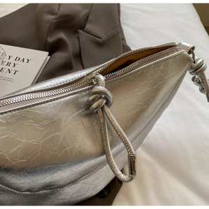 Detail of silver crescent handbag with crinkle texture and knotted shoulder strap