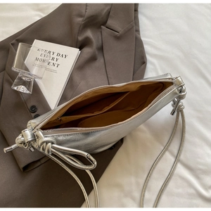 Detail of silver shoulder bag showing brown fabric interior and inner zipper pocket