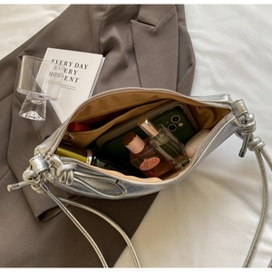 Detail of silver dumpling bag showing yellow lining and interior zipper pocket