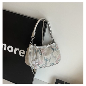 Detail of retro floral jacquard handbag with silver metallic handle and beaded charm