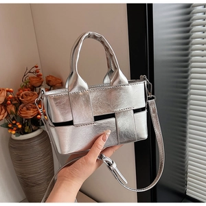 Detail of silver metallic woven handbag with adjustable strap and textured finish