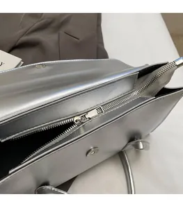 Detail showing high-quality smooth metal zipper on silver metallic shoulder bag