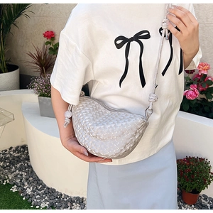 Détail du sac croissant tressé argenté montrant la texture et la bandoulière nouée