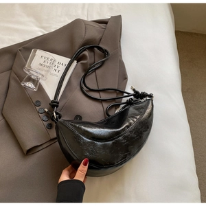 Detail shot of the glossy black crescent saddle bag showing the textured PU leather surface