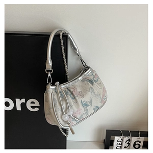 Detail of embroidered floral fabric and silver metal frame on a mini satchel handbag
