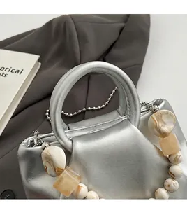 Détail du sac argenté plissé avec poignée en perles marbrées et chaîne à billes