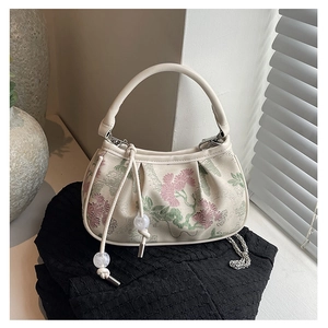 Detail of floral embroidery and pearl bead charm on a cream mini square handbag