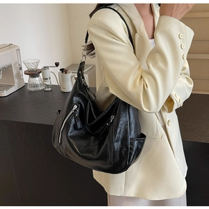 Close-up of black hobo bag with soft pleated leather and stylish silver metallic zippers