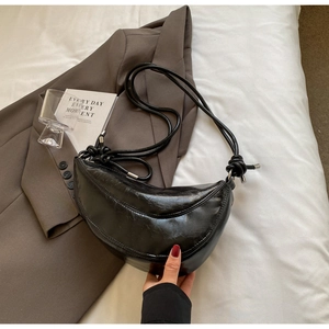 Detail of black pleated crescent bag featuring knotted shoulder strap and silver hardware