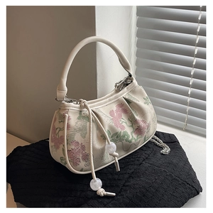 Detail of beige embroidery handbag featuring floral patterns and silver chain strap