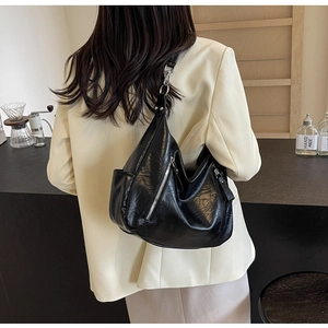 Retro black motorcycle tote bag in shiny faux leather styled with a beige blazer